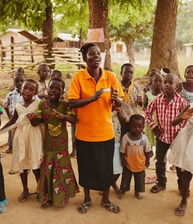 A World Vision employee sings with a group of children