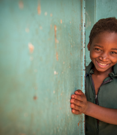 Girl smiling next to green wall