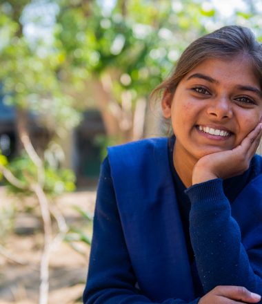 Smiling girl in blue dress resting her head on her hand