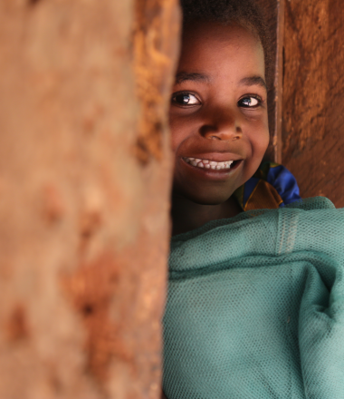 Girl smiling from behind a wall