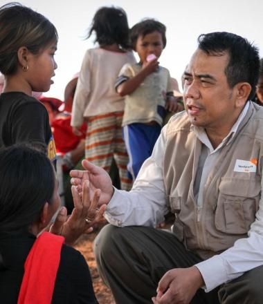 World Vision Cambodia staff member listening to flood affected child from rural village, Cambodia