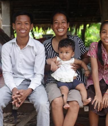 Khmer family with mum and three siblings sit together smiling, Cambodia.