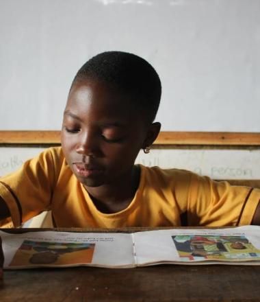Child in yellow shirt reading book at school