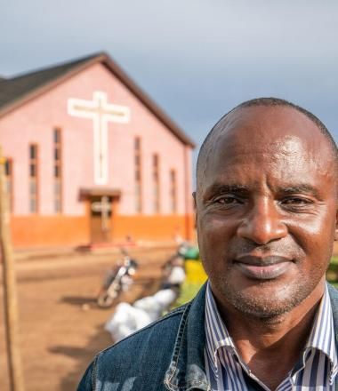 Church leader stands in front of church in the democratic republic of congo