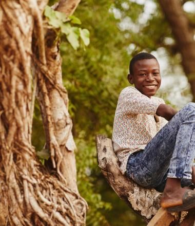 Boy climbing a tree in Ghana