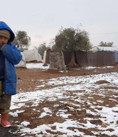 Syrian refugee walks through snow in camp
