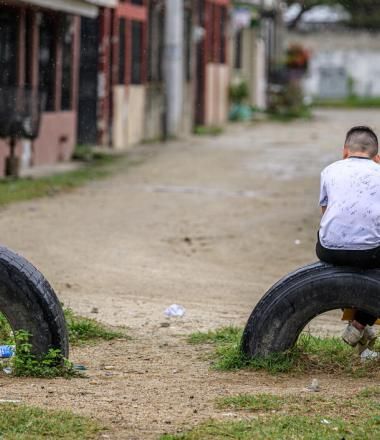 Child sits alone on a tire stuck in the ground