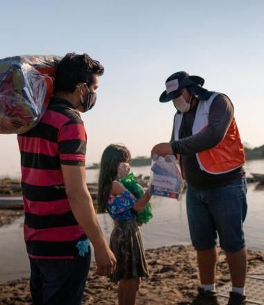 WVI staff gives bags of food to adult man and female child