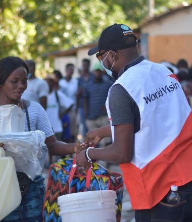 World Vision staff gives food to a woman