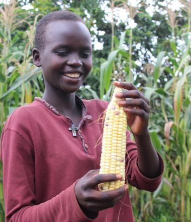 young girl holds up an ear of corn