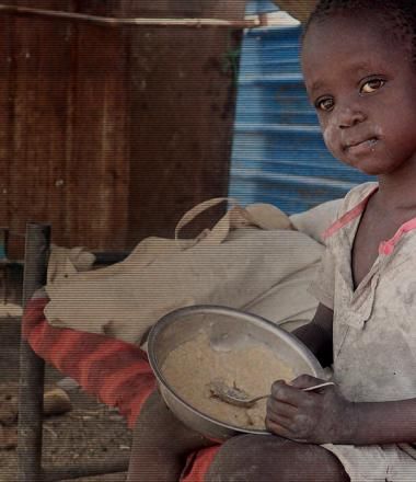 Child with small plate of food in Africa