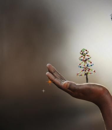 World Vision Child Sponsorship Christmas of Firsts Key Art _ Child looking at beaded Christmas tree in her hand