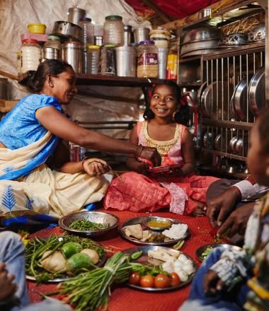 Mother hands food to her daughter as their family eats together