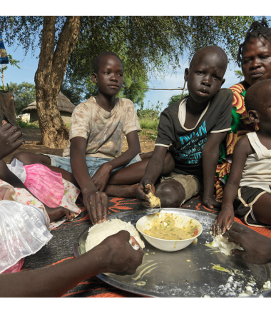 Eight year old, Mandela eats food with his siblings in Juba, South Sudan.