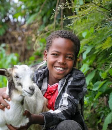 Babi, age 9, holds one of his family's young goats.