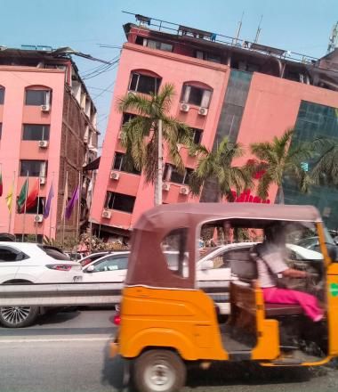 Orange vehicle drives past building damaged in Myanmar