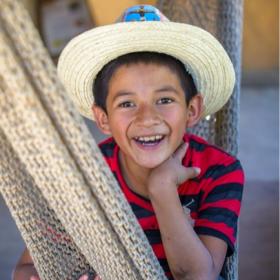 A boy in Mexico smiles while sitting in a hammock