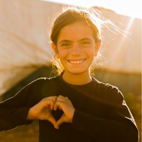 A girl makes a heart shape with her hands