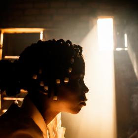 A girl sits in her home with the sun coming in in the background
