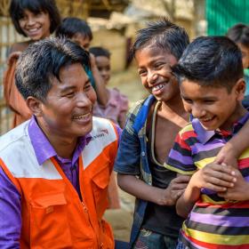 A World Vision employee smiles with some children in Bangladesh