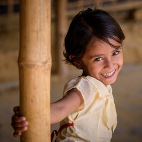 A girl in Bangladesh smiles in her home