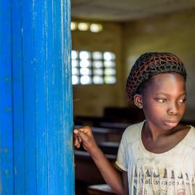 A young girl stands at her school in DRC