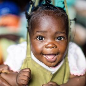 A baby smiles as she gets weighed