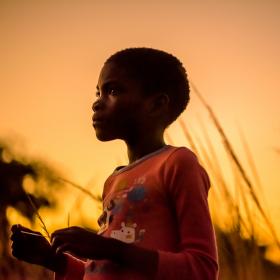 Girl in pink shirt looking at sunset