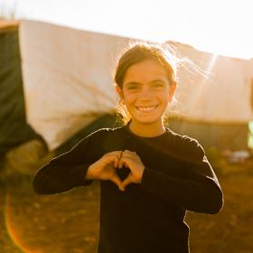 Syrian girl making a hear with her hands at sunset