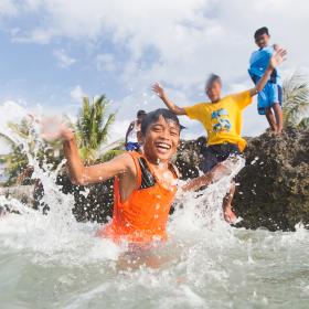 A group of children jump into the ocean in the Philippines