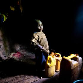 A young Burundi child stands in his home