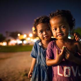 Two young Khmer children stand in the street