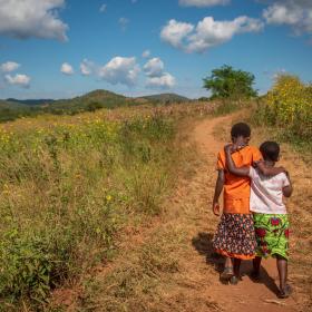 Two children walk down a road in Africa