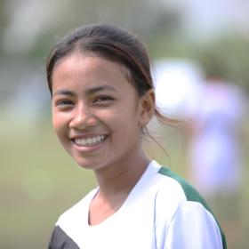 Khmer teenager in football jersey smiles on football pitch