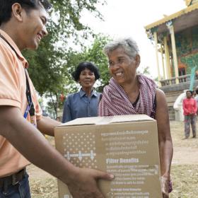 World Vision staff hands community member water filter during flooding event
