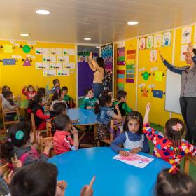 Syrian refugee children leaning how to count with the help of their teachers