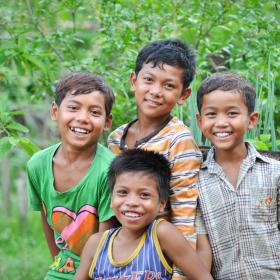 Four Khmer boys smiling at camera standing in garden