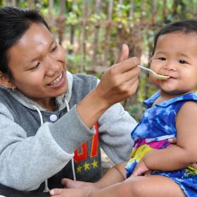 Khmer mum spoon feeds her child traditional Cambodian porridge nutritious food