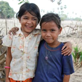 Two Khmer children stand together with their arms around each others shoulders
