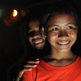 Two young Khmer women stand smiling, it is night time