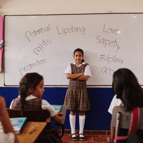 Girl standing in the middle of classroom with her arms crossed