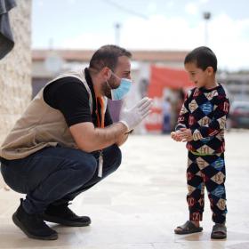 World Vision staff kneeling with young boy