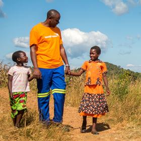 World Vision staff member walks with children in Africa
