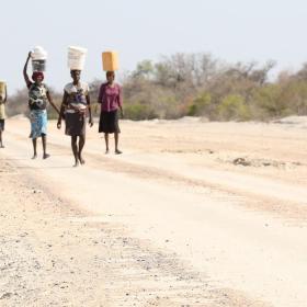 Women and girls walk along a dusty road in Angola looking for water