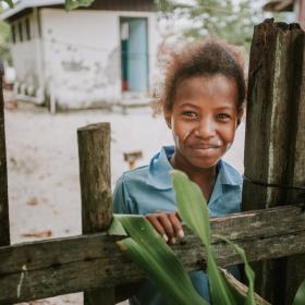 child stands behind fence