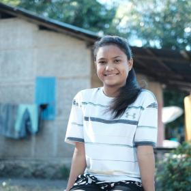 girl sits outside a house smiling