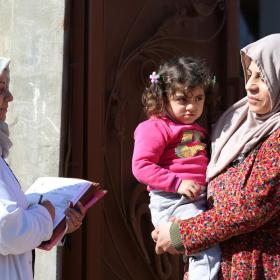 woman speaks to another woman holding a child during a door to door healthcare call
