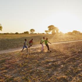 children play futbol in a dirt field