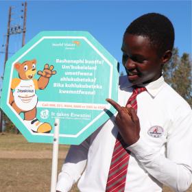 A child posing with a placard which calls for people to report sexual abuse against children in Eswatini
