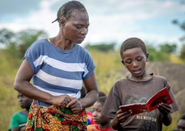 Featured Image: Community reading club volunteer, Jenara Mumbulu, listens to and helps Lightwell, 10, with his reading at a World Vision's reading camp in Zambia. (Photo credit: Laura Reinhardt / World Vision).